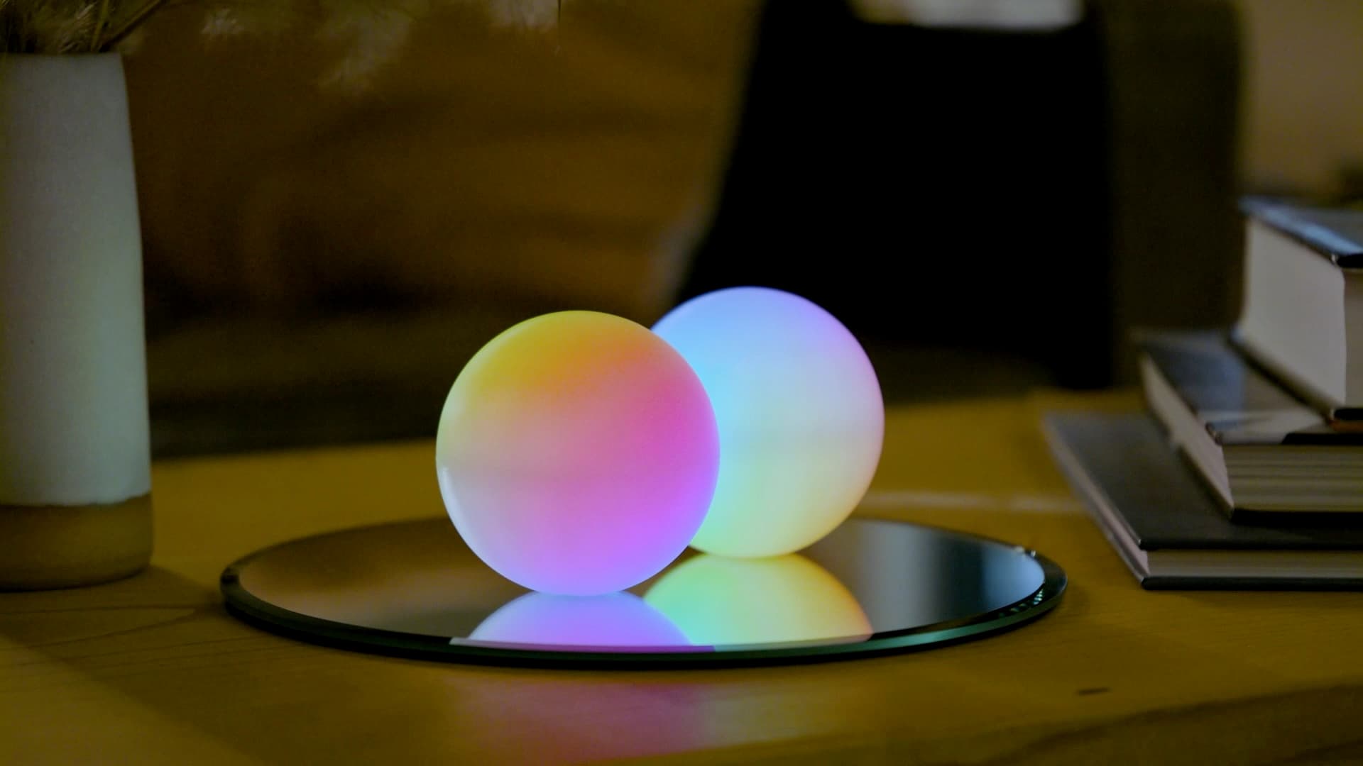 Two Qubi spheres on a mirror, reflecting colorful light