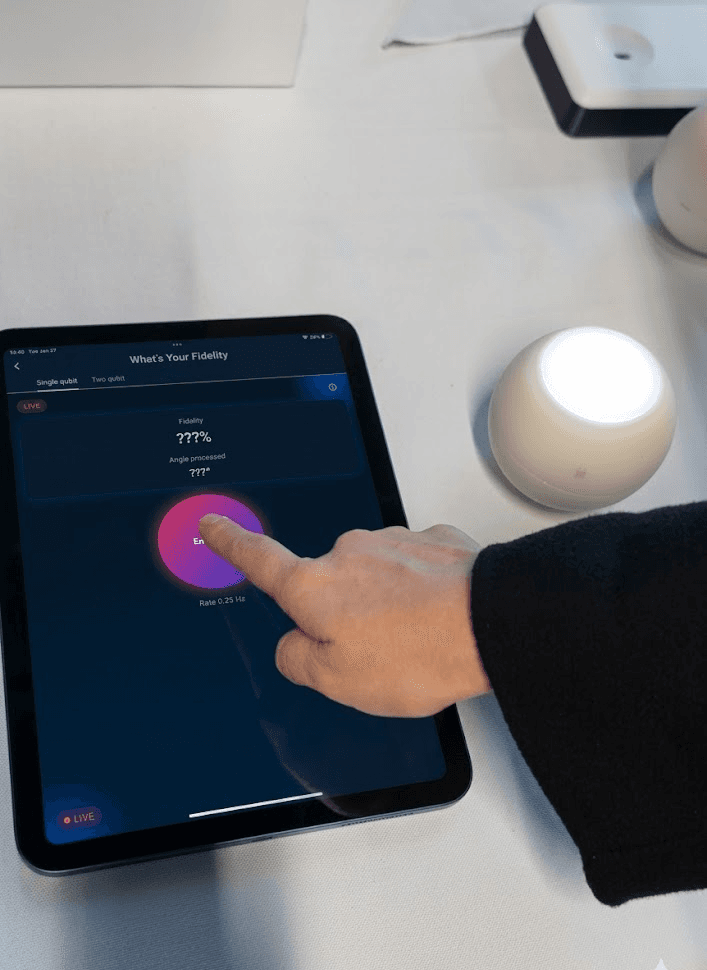 Hand tapping the What's Your Fidelity app on a tablet next to a Qubi
